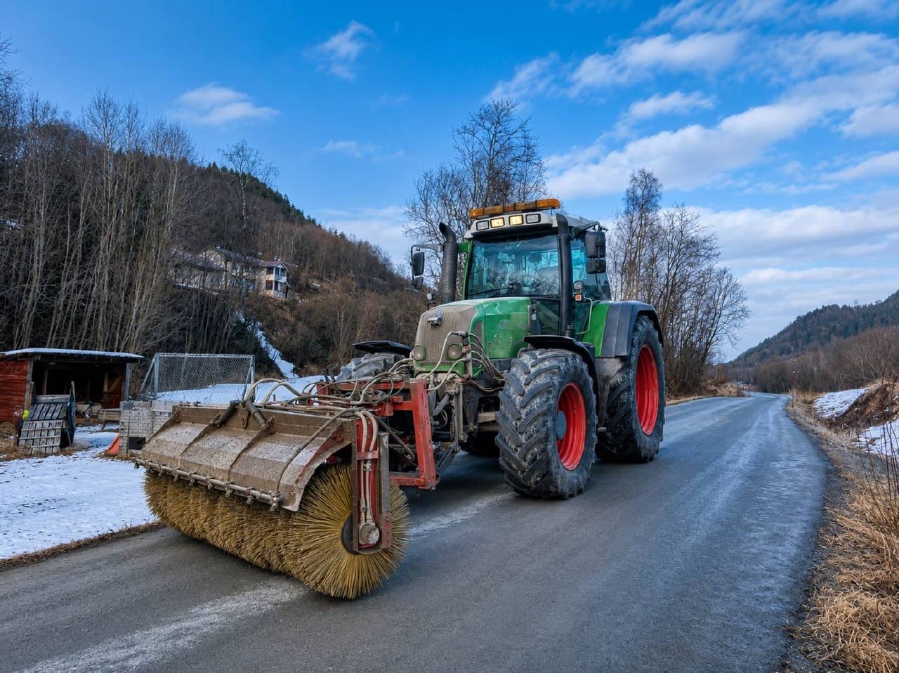 Traktor med kost feier veien etter vinteren